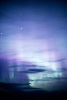 The Northern Lights emerge through the clouds in remote Alaska