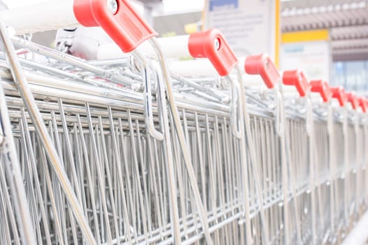 Rows of shopping carts on car park near entrance of supermarket