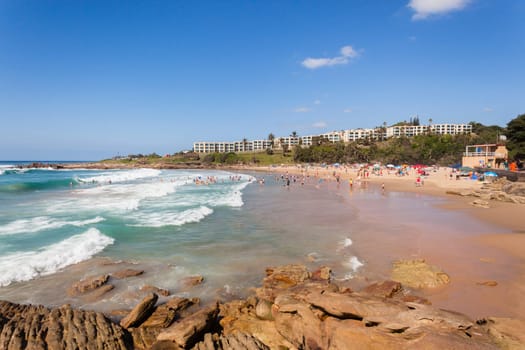 Ocean waves swimmers men women boys girls  in beach rocky landscape