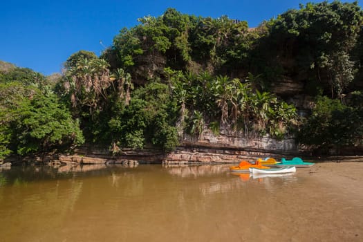 River beach lagoon rocky coastline with paddle boat canoes landscape