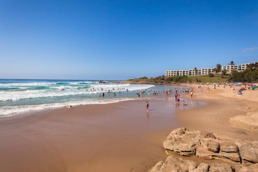 Ocean waves swimmers men women boys girls  in beach rocky landscape