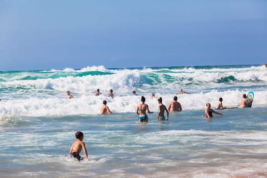 Ocean waves swimmers men women boys girls  in beach rocky landscape