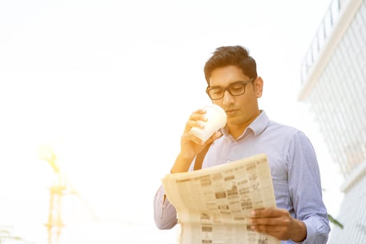 Asian Indian business people drinking coffee and reading newspaper on the way to work place. Handsome male model.