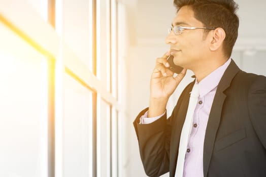 Indian estate agent checking on new office to let and calling on phone.