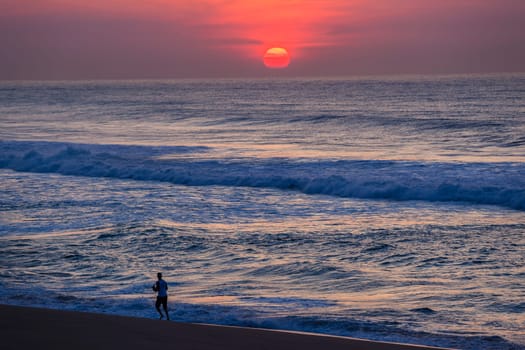 Ocean sunrise new day with runner along beach shoreline landscape