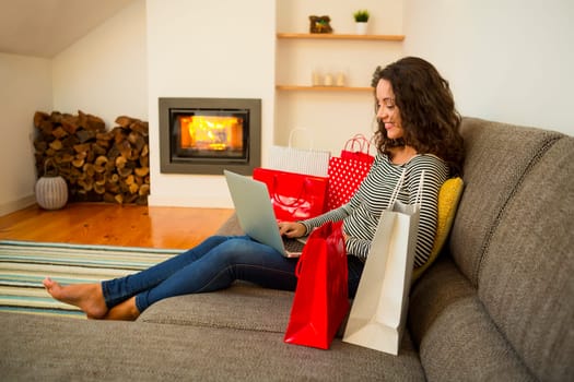 Beautiful woman at home at the warmth of the fireplace, shopping online