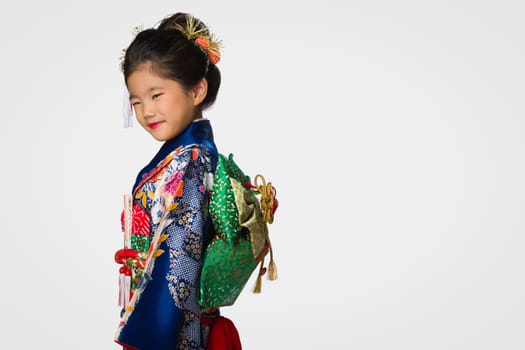 A cute young Japanese girl wearing a Kimono on a white background.