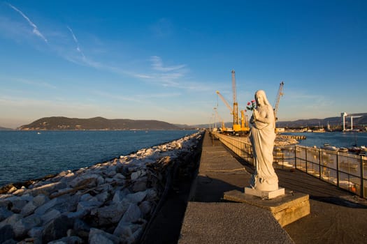 Close up view of the Virgin Mary patroness of seafarers and port with cranes in the background