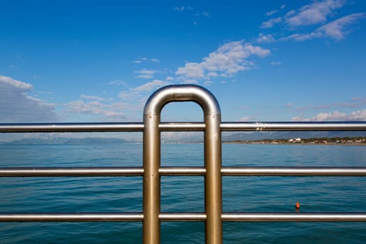 Close up view of the railing of a pier with marine landscape in the background