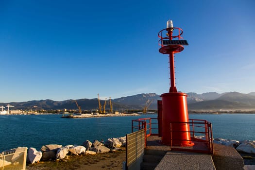 Costal landscape with lighthouse in the foreground, the commercial port and the mountain range in the background