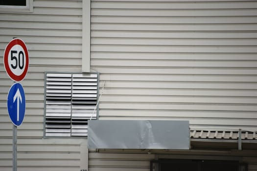 Roof boards and a stainless steel ventilation grille on a sheet metal wall of a public shopping building.