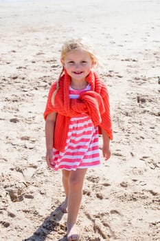 Little girl on the beach smiling at the camera.