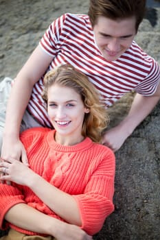 Beautiful romantic young couple on the rocks at the seaside. They are smiling and look very content together