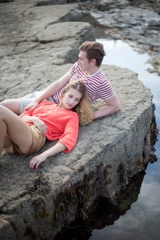 Beautiful couple lying on the rocks at the beach.