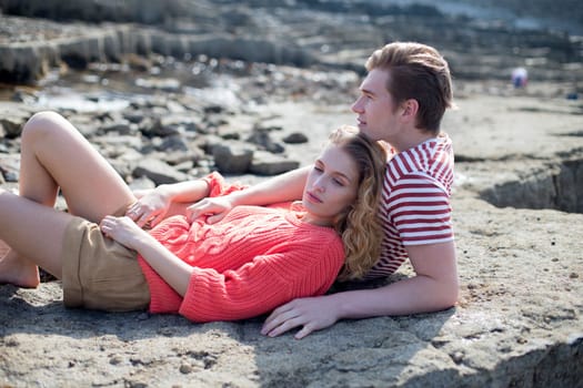 Beautiful couple lying on a rock at the beach. They look very happy and content together.