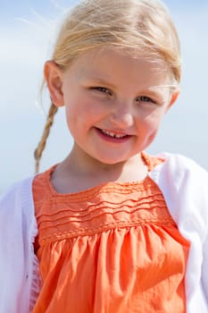 Close up of a beautiful little girl outdoors. She is wearing casual clothing and smiling at the camera.