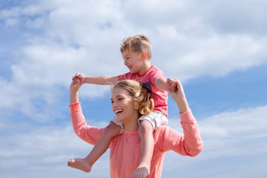 Mother and Son on the background of bright blue sky. They are laughing and smiling.