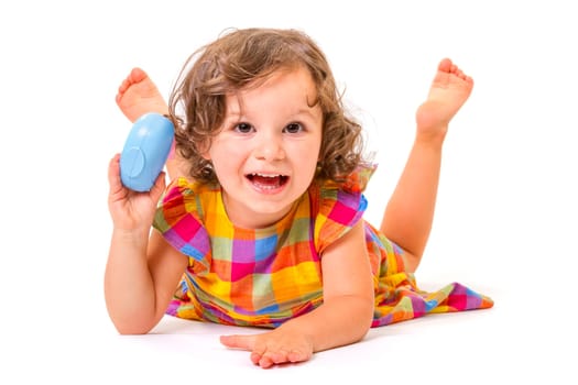 Cheerful little girl smiling at camera lying on white background.