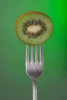 Kiwi fruit on fork over color background, concept photo. Ideal for healthy eating campaign or fitness poster.