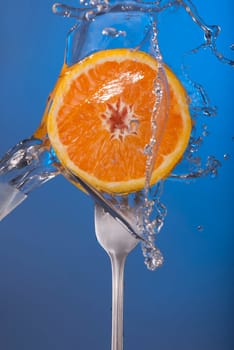 Orange fruit on fork with water splash and color background, concept photo. Ideal for healthy eating campaign or fitness poster.