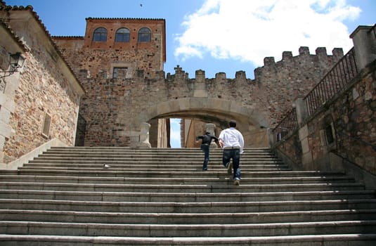 Two guys running up the Estrella Arch stairs, at Caceres Old Town