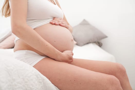 Young new mother is sitting on a bed