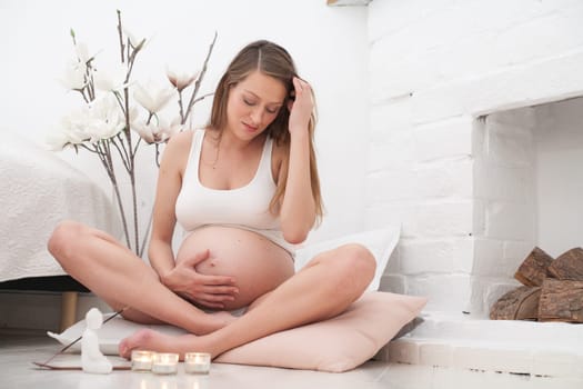 Young new mother is meditating on the ground of her bedroom