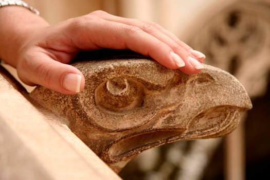 A woman hand rest over stone gargoyle. Toledo, Spain