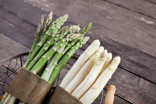 fresh green and white asparagus in a basket on a wooden background
