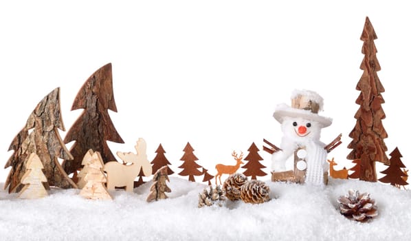 Wooden decoration arranged as a cute winter scene with a snowman,conifer trees,animals and snow,isolated on white background