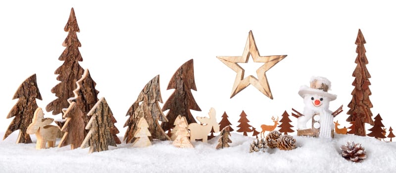 Wooden decoration arranged as a cute winter scene with a snowman,conifer trees,Christmas star,animals and snow,isolated on white background
