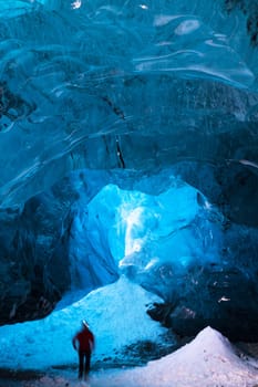 Person hiking inside an icecave in south iceland, person is motion blurred