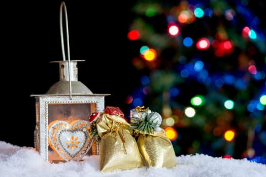 Christmas background with burning lantern in the snow and bokeh