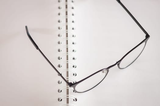 Eyeglasses on opened spiral notebook , stock photo