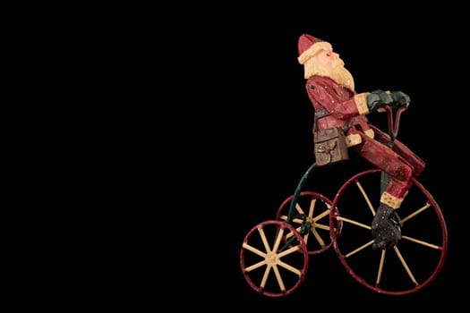 Christmas decoration with santa sitting on a tricycle, copy space, isolated on black