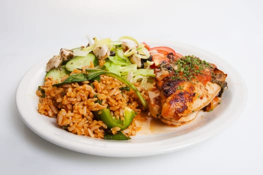 Plate of prepared chicken dinner shot on white with rice and salad