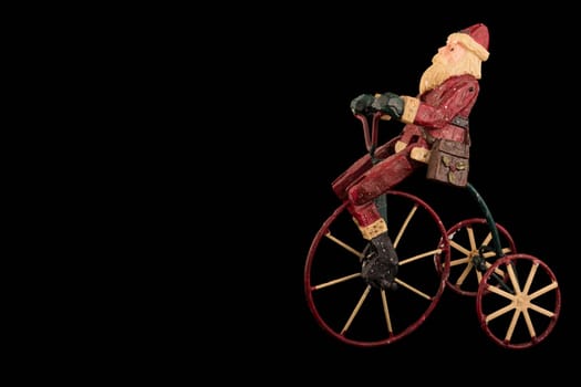 Christmas decoration with santa sitting on a tricycle, copy space, isolated on black