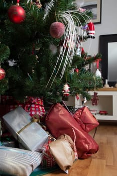 Cropped shot of presents under a decorated christmas tree in a real living room