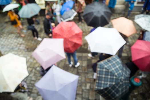 Out of focus shot of people with umbrellas on a rainy day