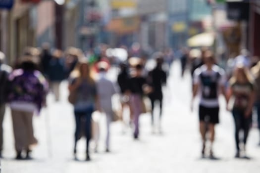 Out of focus shot of people walking on a shopping street in summer