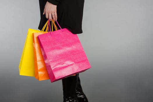 Cropped shot of a woman with shopping bags on grey