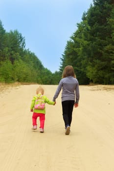 little sisters go on a forest road holding hands