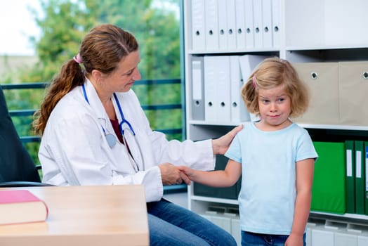 female pediatrician in white lab coat greeting a fearful little girl