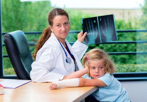 female pediatrician in white lab coat examined little girl