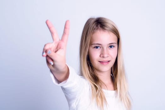 nice blond girl in front of gray background showing victory sign