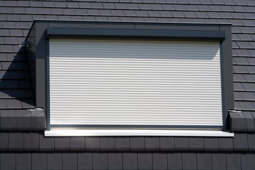 Porthole with a white rolling shutter on a black roof