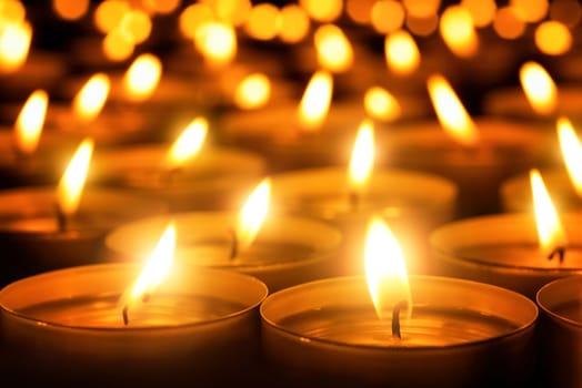 Many candle flames glowing in the dark,create a spiritual atmosphere
