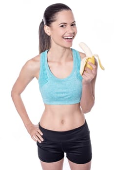 Young fit smiling woman eating banana