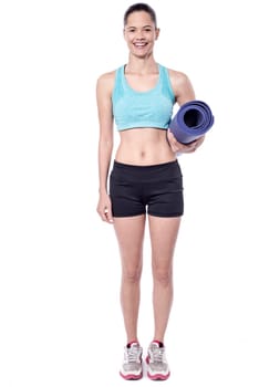 Female yoga trainer holding exercise mat