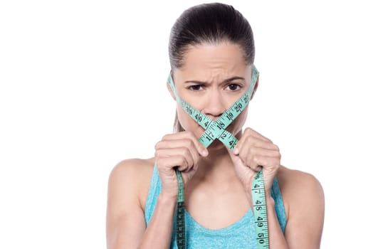 Tensed young woman holding measuring tape